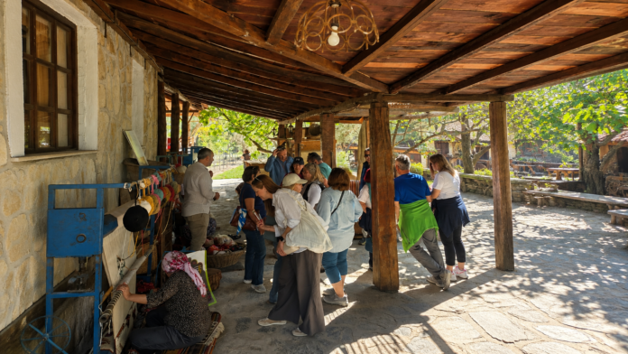 AUTHENTIC TURKISH VILLAGE EXPERIENCE NEAR BODRUM showing visitors exploring a traditional stone village house with wooden architecture, local culture, handmade crafts, and authentic countryside atmosphere near Bodrum, Turkey.